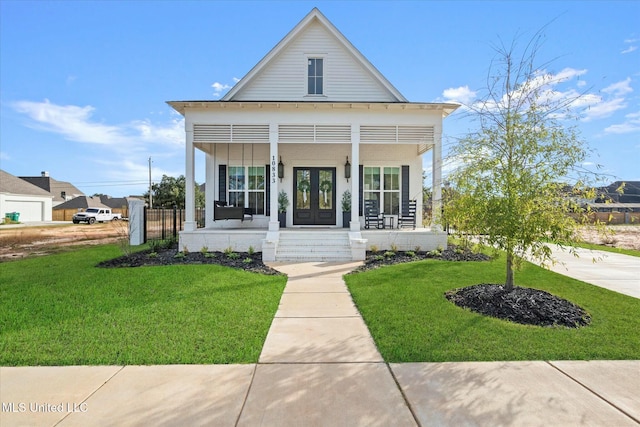 view of front of house with a front lawn, covered porch, and french doors