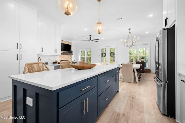 kitchen with pendant lighting, white cabinets, blue cabinets, stainless steel fridge, and a barn door