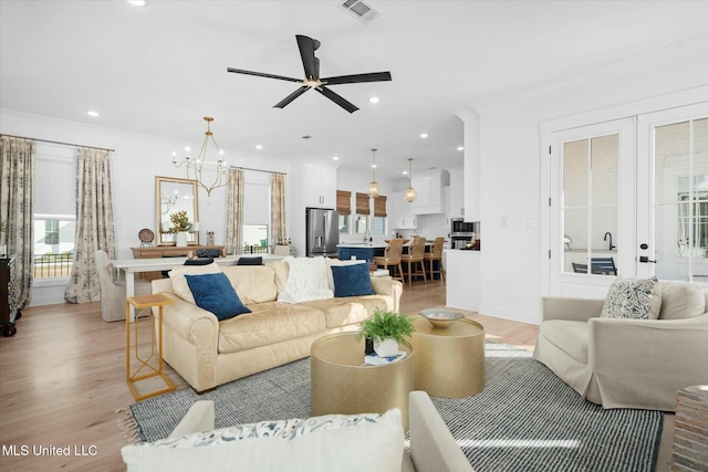 living room featuring ceiling fan with notable chandelier, french doors, and light hardwood / wood-style flooring