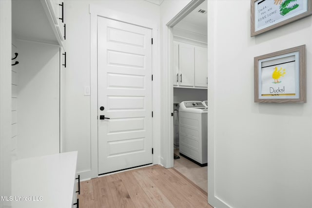 laundry area with light hardwood / wood-style floors, cabinets, and washer / clothes dryer