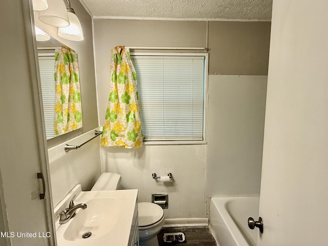 bathroom featuring a textured ceiling, toilet, a washtub, vanity, and wood finished floors