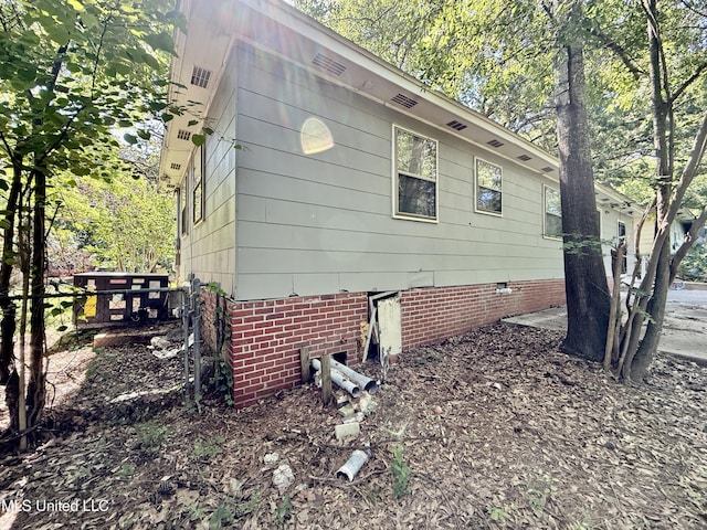 view of side of home with crawl space and fence