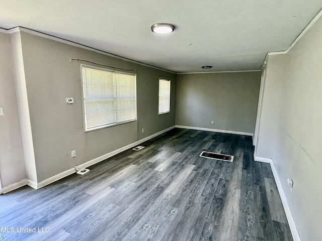 empty room featuring visible vents, wood finished floors, baseboards, and ornamental molding