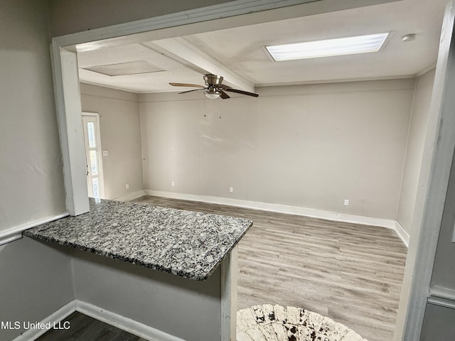 spare room featuring baseboards, beam ceiling, ceiling fan, and wood finished floors