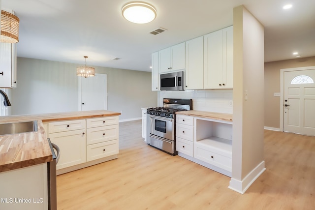 392 Lawler Ave, Long Beach, MS 39560 - kitchen featuring butcher block counters, appliances with stainless steel finishes, light wood-style flooring, a sink, and decorative backsplash
