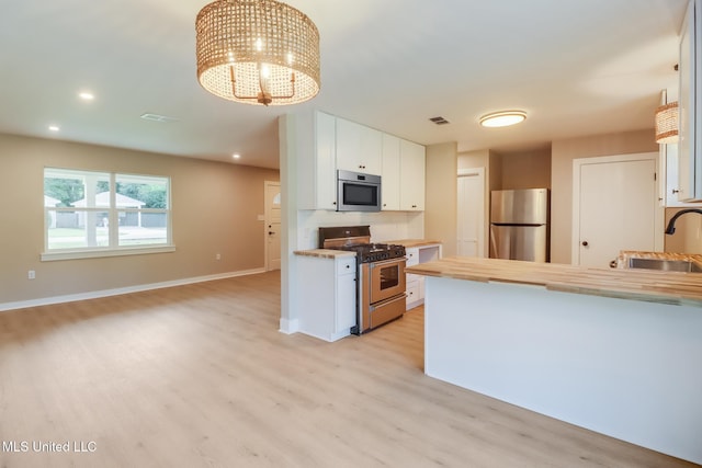 392 Lawler Ave, Long Beach, MS 39560 - kitchen with stainless steel appliances, a sink, light wood finished floors, white cabinetry, and a chandelier