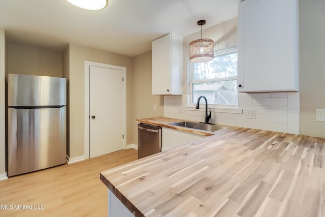 392 Lawler Ave, Long Beach, MS 39560 - kitchen with stainless steel appliances, butcher block counters, a sink, white cabinets, and light wood-type flooring