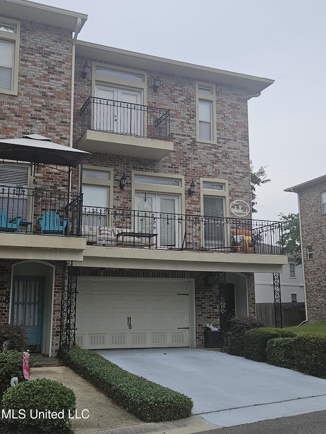 21 Oak Alley Ln, Long Beach, MS 39560 - townhome / multi-family property featuring a balcony, brick siding, driveway, and an attached garage
