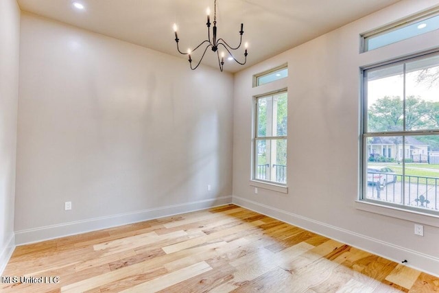 empty room featuring a chandelier and light wood-type flooring