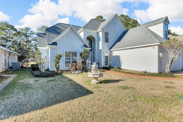 view of front of house featuring a front lawn, a garage, and cooling unit