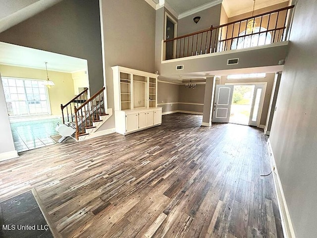 unfurnished living room featuring crown molding, a towering ceiling, and hardwood / wood-style flooring