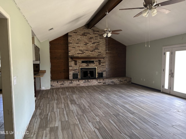 unfurnished living room featuring ceiling fan, beam ceiling, high vaulted ceiling, a fireplace, and light hardwood / wood-style floors