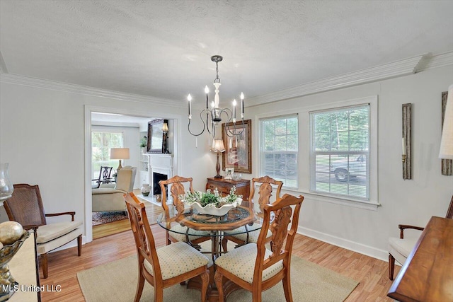 dining area featuring an inviting chandelier, crown molding, a textured ceiling, and light hardwood / wood-style floors