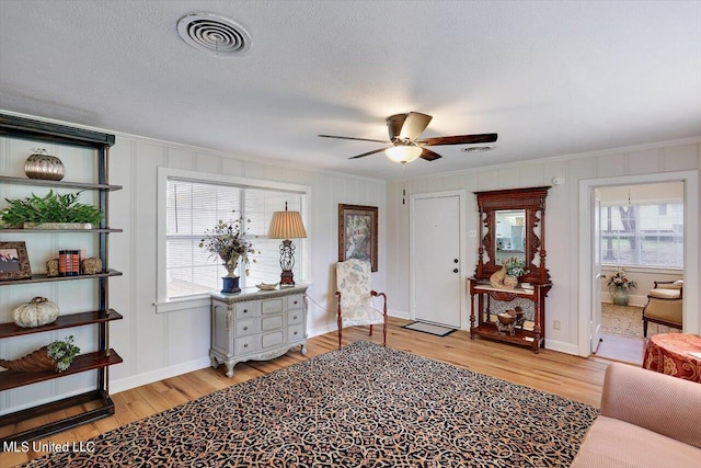 sitting room featuring ceiling fan, crown molding, a textured ceiling, and light wood-type flooring