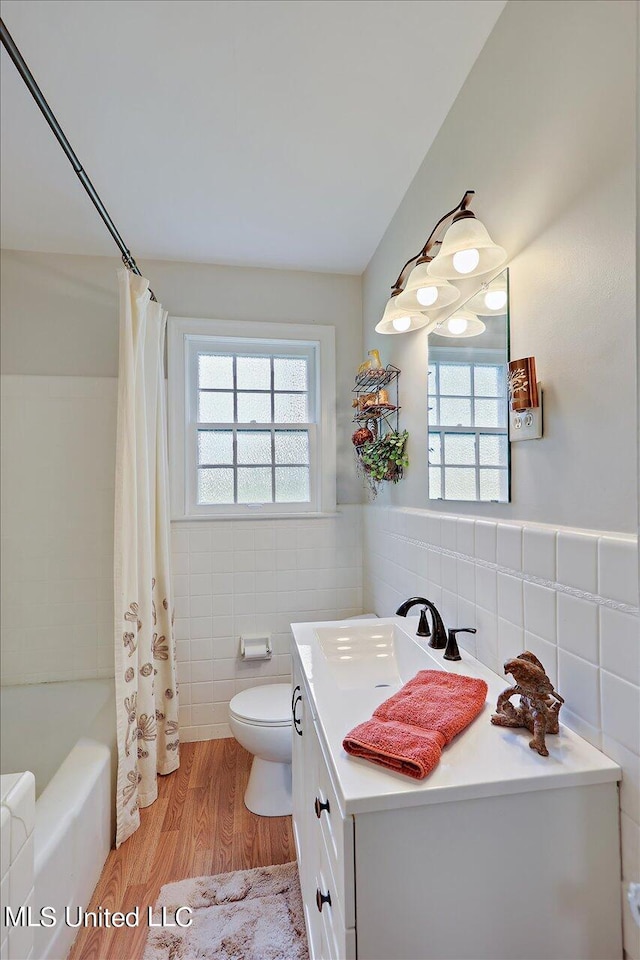 full bathroom featuring hardwood / wood-style flooring, toilet, vanity, tile walls, and shower / bathtub combination with curtain