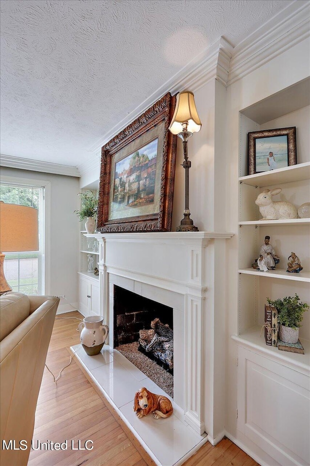 living room with light hardwood / wood-style floors, a textured ceiling, and ornamental molding