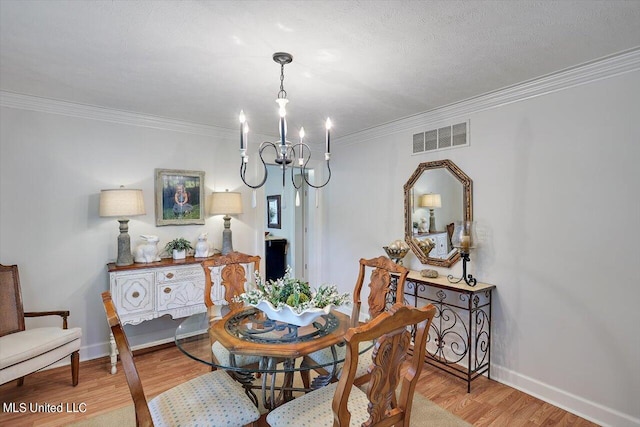 dining space featuring crown molding, a textured ceiling, light hardwood / wood-style flooring, and an inviting chandelier