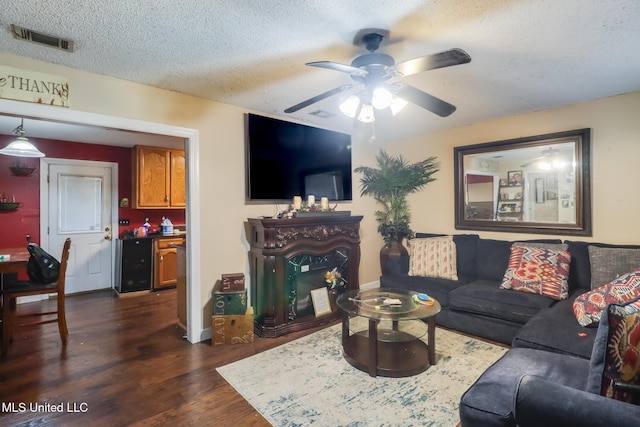 living room featuring ceiling fan, dark wood-type flooring, bar area, and a textured ceiling