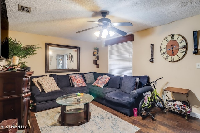 living room with a textured ceiling, dark hardwood / wood-style floors, and ceiling fan