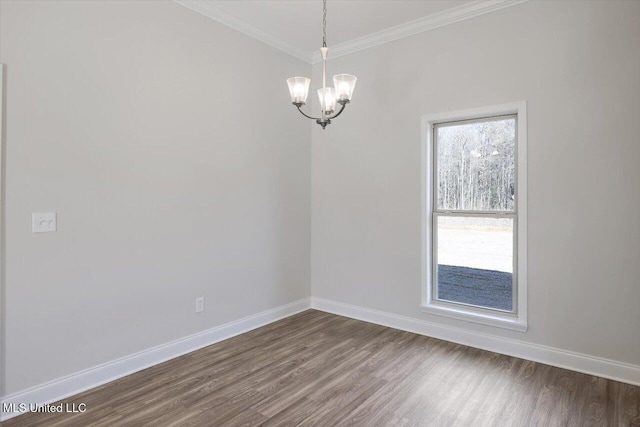 empty room with hardwood / wood-style flooring, crown molding, and a chandelier