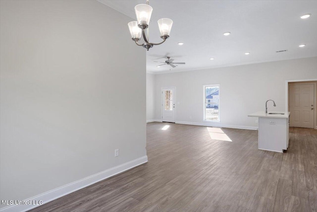 unfurnished living room featuring ceiling fan with notable chandelier, ornamental molding, dark hardwood / wood-style floors, and sink