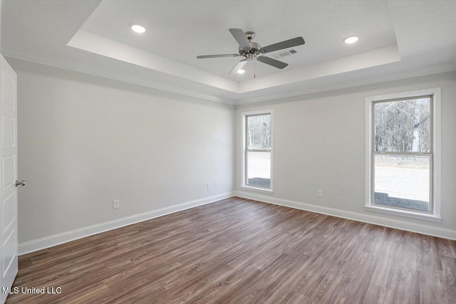 spare room featuring dark hardwood / wood-style floors, ceiling fan, and a tray ceiling