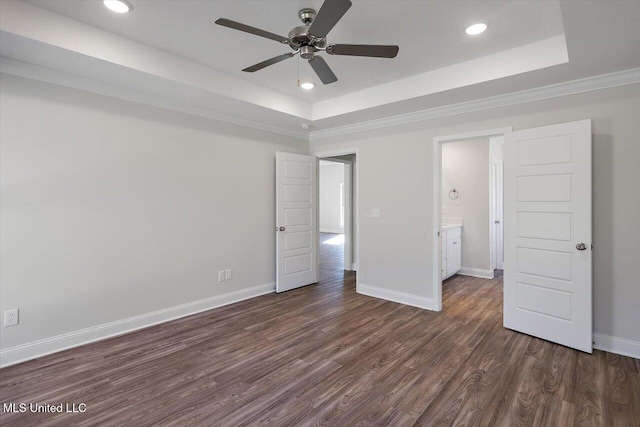 unfurnished bedroom featuring crown molding, ceiling fan, a tray ceiling, and dark hardwood / wood-style flooring