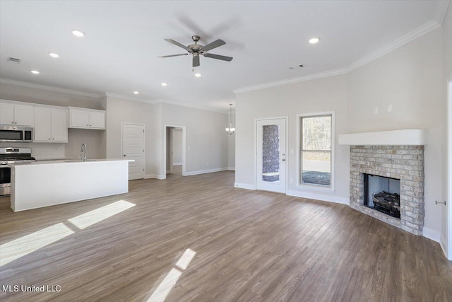 unfurnished living room featuring crown molding, a fireplace, ceiling fan, and light wood-type flooring