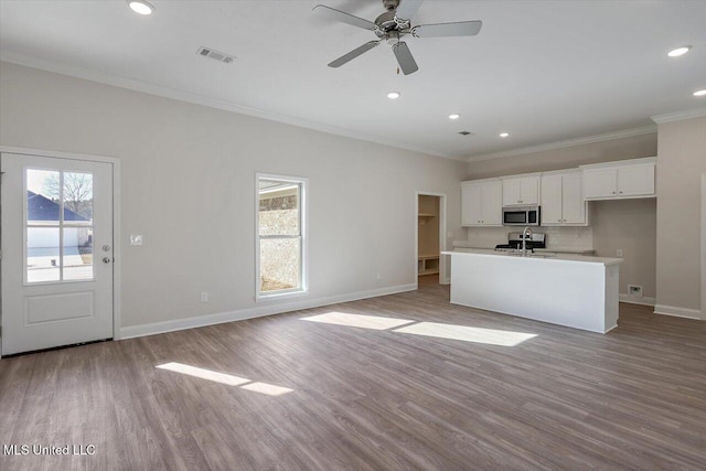 kitchen with sink, light hardwood / wood-style flooring, a kitchen island with sink, white cabinetry, and ornamental molding