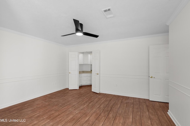 unfurnished bedroom with visible vents, hardwood / wood-style floors, ornamental molding, ceiling fan, and baseboards