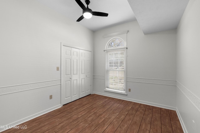 unfurnished bedroom with dark wood-type flooring, multiple windows, and baseboards