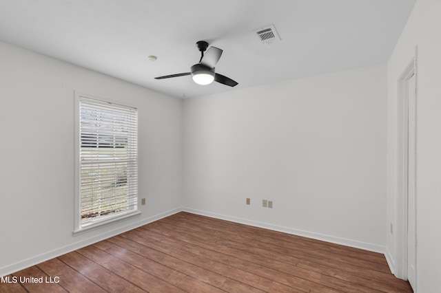 unfurnished room with a ceiling fan, wood finished floors, visible vents, and baseboards