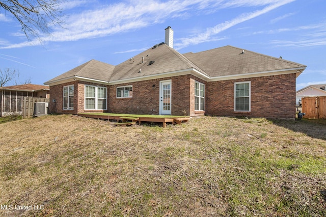 back of house featuring central air condition unit, a chimney, fence, and brick siding