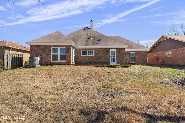 rear view of house with brick siding, a lawn, fence, and central air condition unit