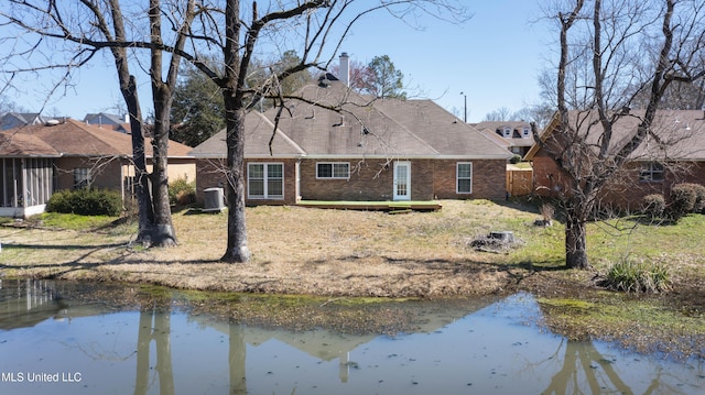 back of property featuring a chimney, brick siding, a water view, and central AC