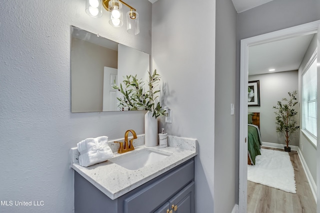 bathroom with wood finished floors, vanity, and baseboards
