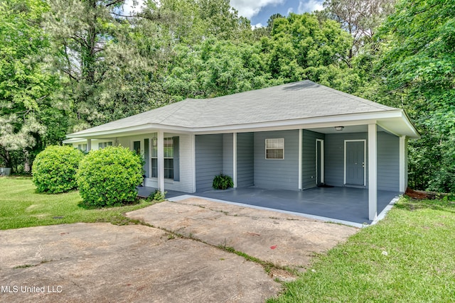 view of front of home featuring driveway, a front yard, a carport, and roof with shingles