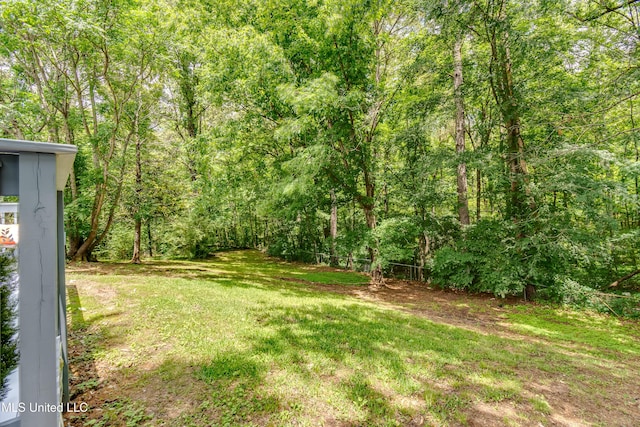 view of grassy yard with a forest view