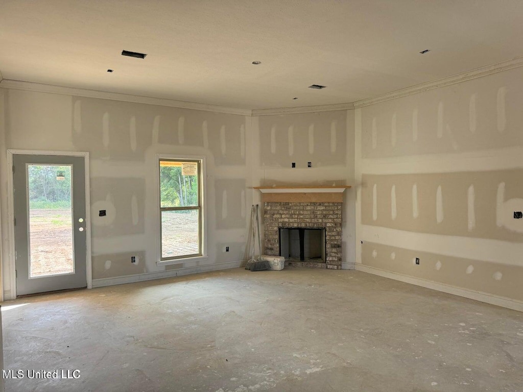 unfurnished living room featuring a wealth of natural light, crown molding, and a fireplace