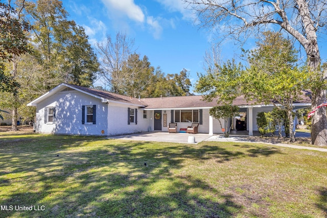 rear view of property featuring a patio area, a lawn, and brick siding