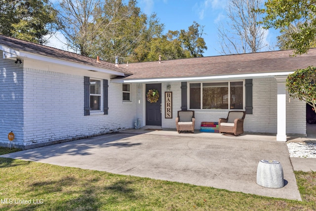 exterior space featuring roof with shingles and brick siding