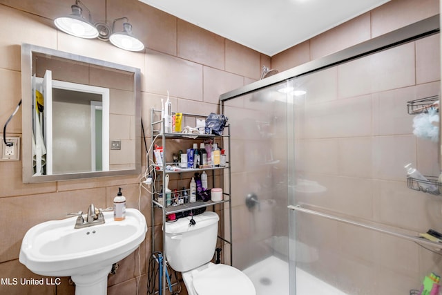 full bath featuring a sink, a stall shower, backsplash, and tile walls