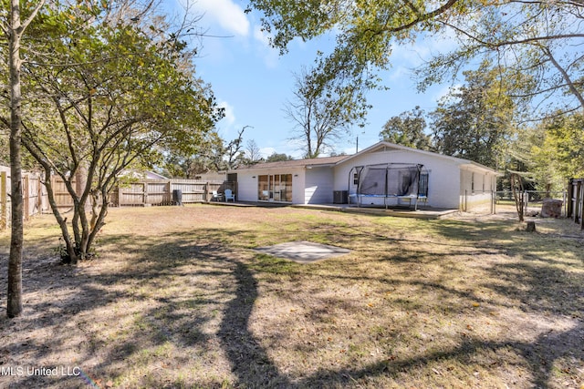 back of property featuring a trampoline, a fenced backyard, a gate, and a yard