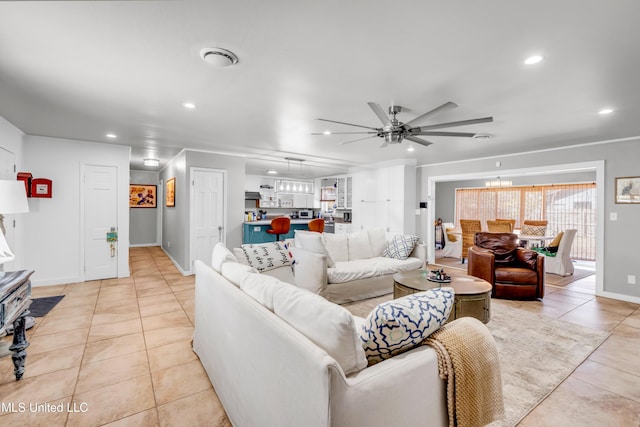 living room featuring light tile patterned floors, baseboards, ceiling fan with notable chandelier, and recessed lighting