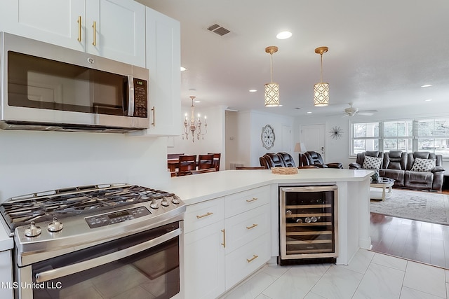 kitchen featuring white cabinetry, ceiling fan, stainless steel appliances, wine cooler, and pendant lighting