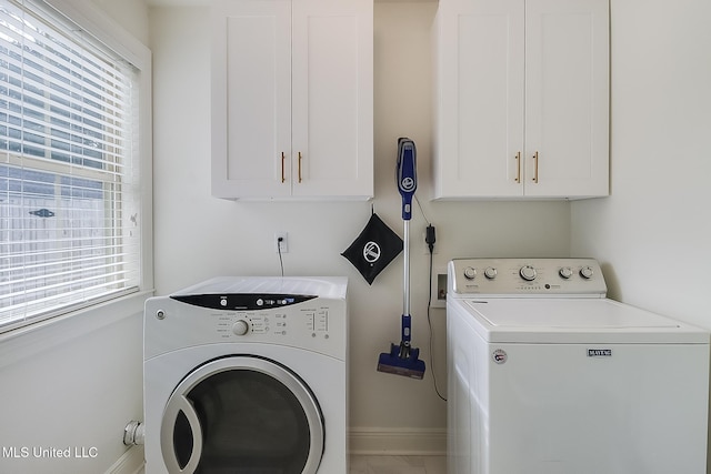 laundry area with a wealth of natural light, separate washer and dryer, and cabinets