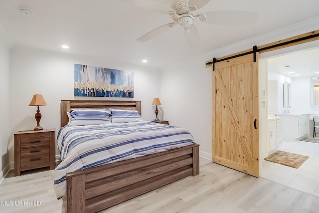 bedroom featuring ceiling fan, crown molding, ensuite bath, and a barn door