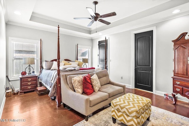 bedroom with dark hardwood / wood-style flooring, ornamental molding, ceiling fan, and a raised ceiling