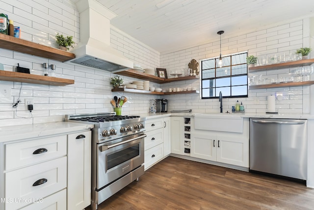 kitchen featuring white cabinetry, premium range hood, light stone countertops, pendant lighting, and appliances with stainless steel finishes