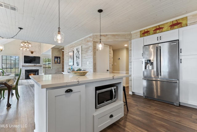 kitchen featuring decorative light fixtures, white cabinetry, light stone counters, and appliances with stainless steel finishes